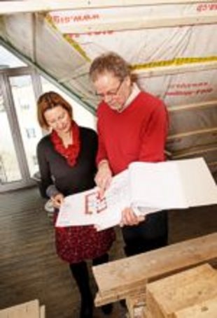 Bauherrenberater erläutert einer Bauherrin anhand eines Plans den Dachausbau