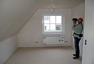 Mann mit Wärmebildkamera in Dachgeschoß-Wohnraum