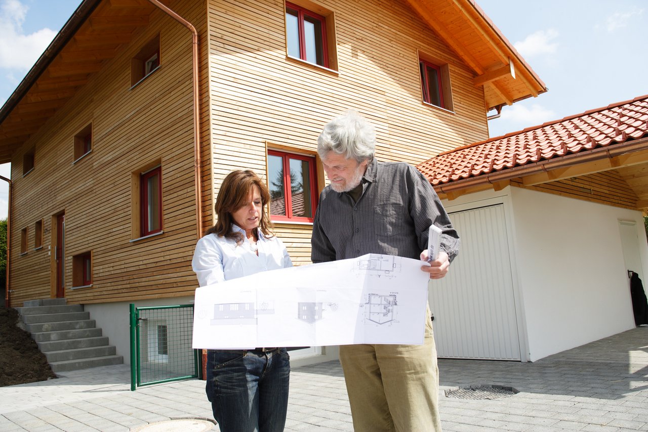 Bauherrenberater Gerhard Schoberth und Bauherrin vor fertiggestelltem Haus